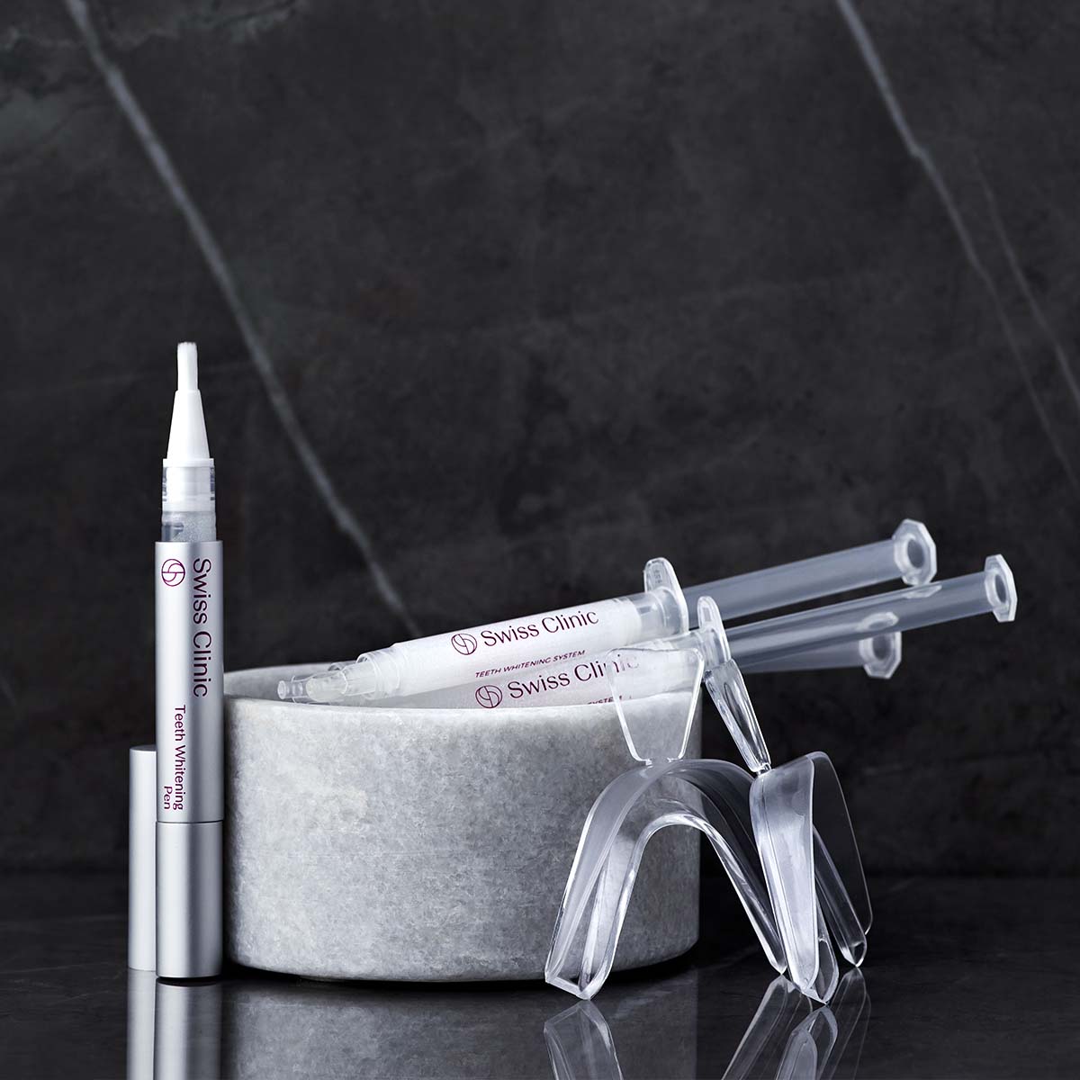 Total Whitening System med Whitening System och Teeth Whitening Pen mot en svart marmorskiva